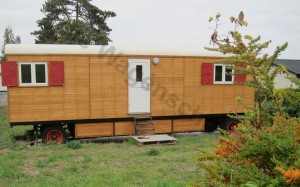 Der Bauwagen im Garten, gsäumt von zarten Büschen.