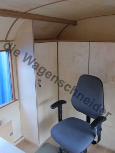 Büro mit Schreibtisch, Einbauschränken und Kurbelfenster.