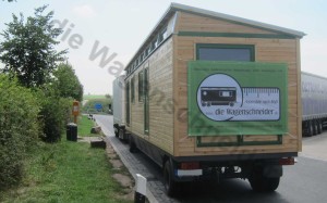 Zugfahrzeug mit Zirkuswagen auf einem Autobahnrastplatz.