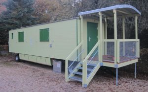 Der Waldkindergartenwagen der KITA "St. Petronilla" in Aulhausen, steht unweit eines Pferdehofes in mitten hoher Fichten.